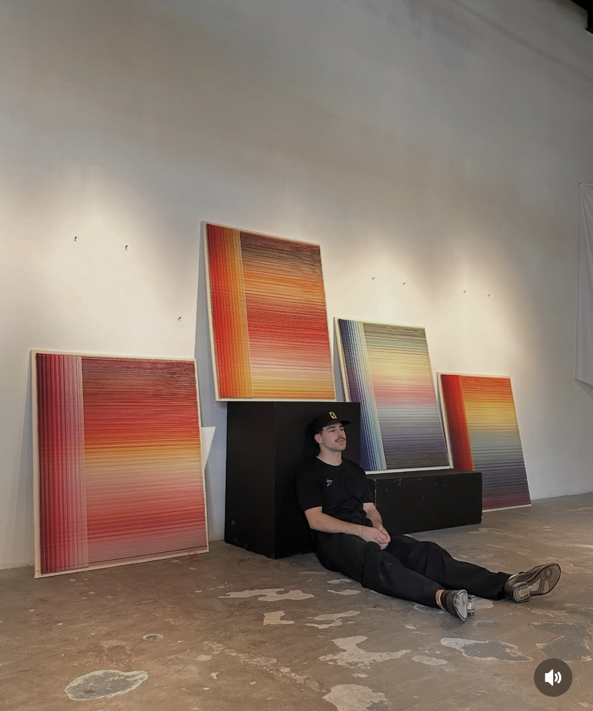 Valentin Elias Renner seated on the gallery floor with four gradient thread works at Modeka.art in Manila